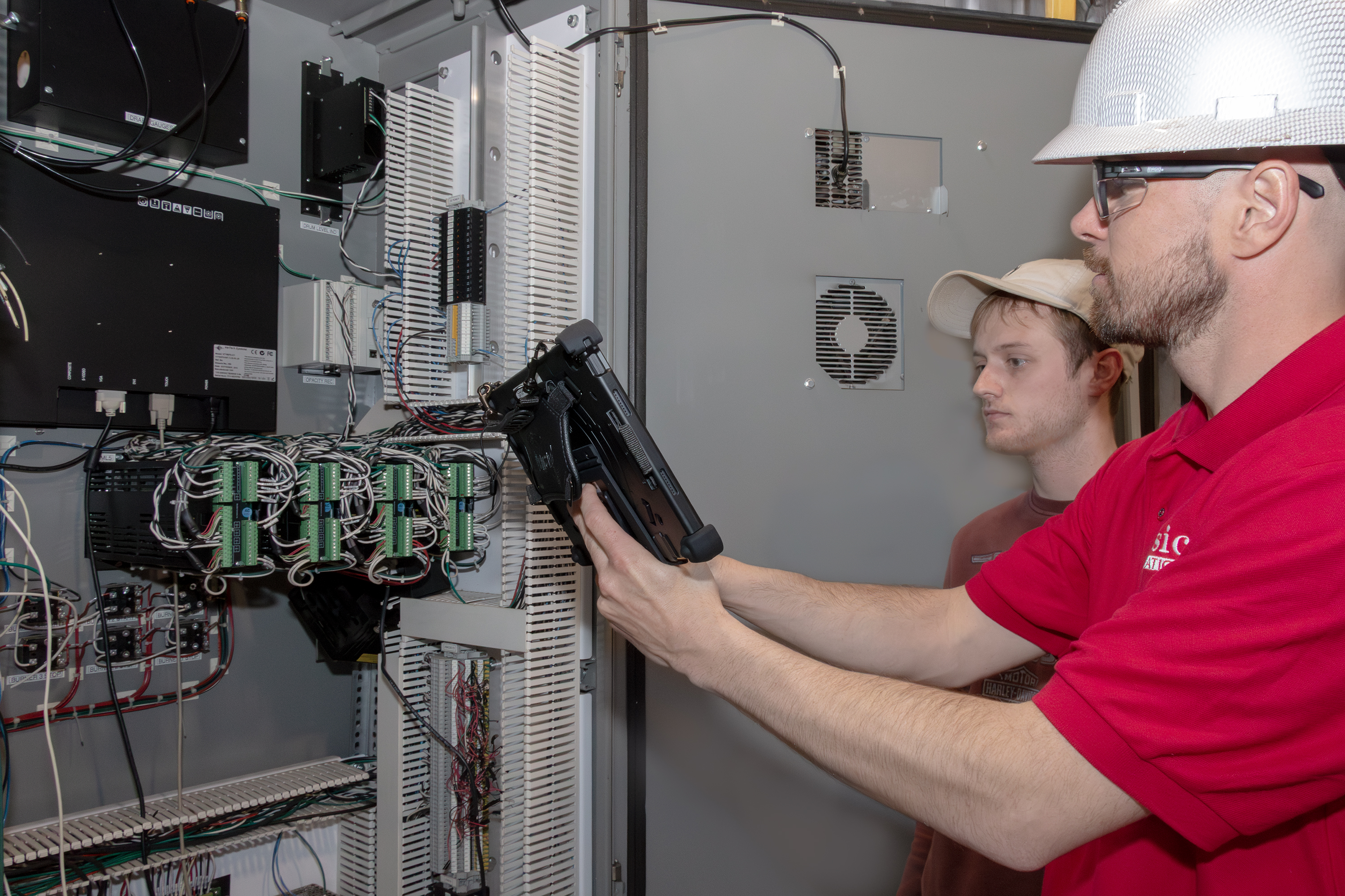 Technicians performing an on-site control system audit with tablet interface at an industrial panel, part of Classic Automation’s audit program.